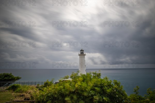 Le Phare du Vieux-Fort, white lighthouse on a cliff. Dramatic clouds with a view of the sea. Pure