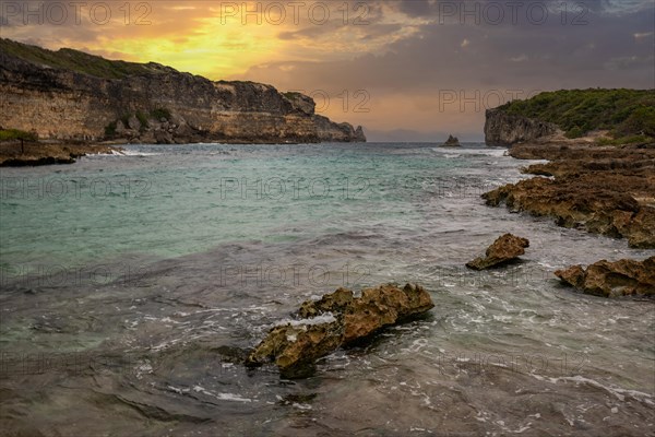 Rocky coast, long bay by the sea at sunset. Dangerous view of the Caribbean Sea. Tropical climate