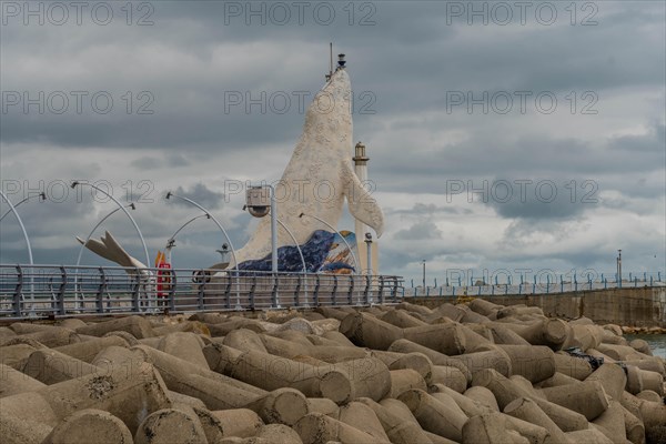 Mosaic fish sculpture on the harbor edge with street lamps and cloudy skies, in Ulsan, South Korea,