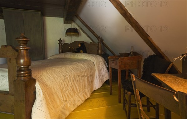 Antique wooden four-poster single bed and armoire in bedroom on upstairs floor inside old 1785