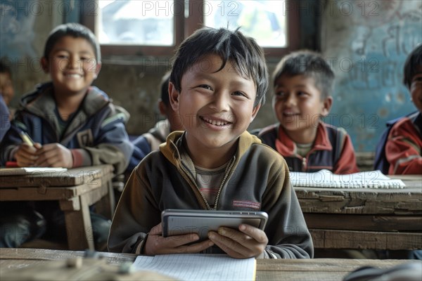 Preschool boy sitting in the classroom with a digital tablet and looking smiling into the camera,