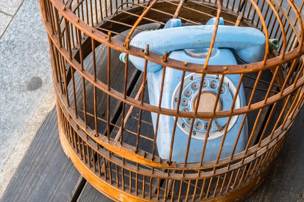 Old style rotary phone sitting in birdcage sitting outside on wooden step in Seoul, South Korea,