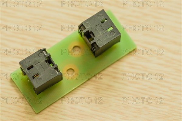 Two black plastic electrical connectors on a green circuit board, in South Korea