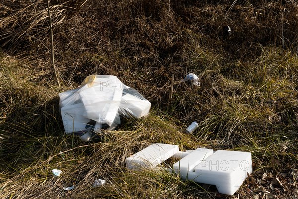 Discarded polystyrene containers scattered in a field showcasing environmental neglect, in South
