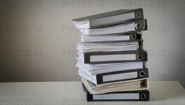 A high pile of files on a table symbolises a large workload, symbolism bureaucracy, AI generated,