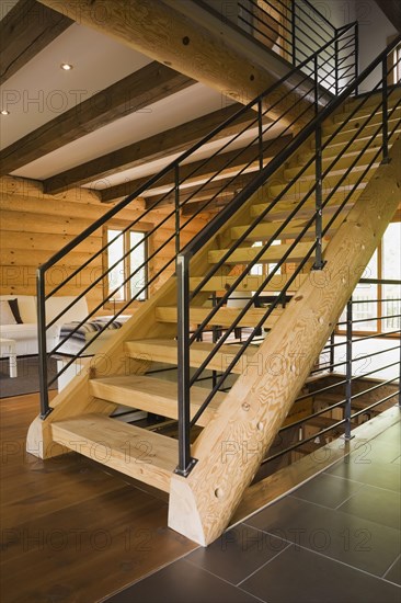 Wooden log stairs with black wrought iron railings and white cotton cloth upholstered sofas in