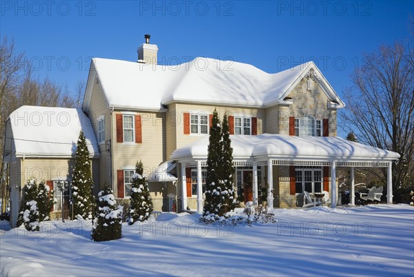 Two story beige vinyl siding with brownish red nuanced brick veneer and orange trim home in winter,