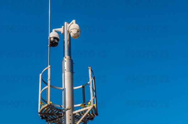 Closed circuit television devices and weather veins on metal pole against blue sky in Daejeon,