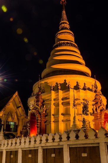 Illuminated temple with golden lights stands out against the dark night, in Chiang Mai, Thailand,