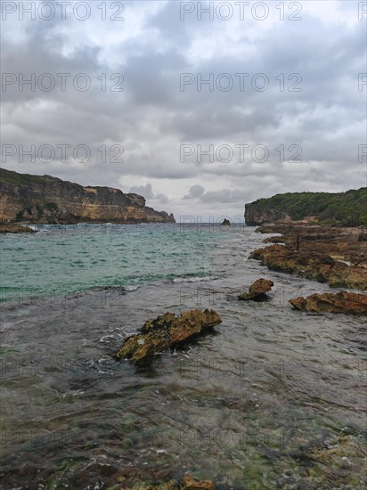 Rocky coast, long bay by the sea at sunset. Dangerous view of the Caribbean Sea. Tropical climate