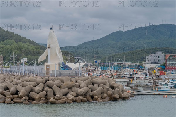 Harbor view with a white lighthouse, docked boats, and tetrapod breakwater, in Ulsan, South Korea,