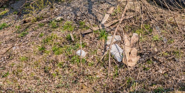 Discarded plastic and debris in a dry grassy area indicating environmental pollution, in South