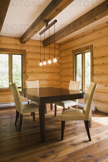 Brown wooden table and white cotton cloth upholstered high back chairs in dining room inside