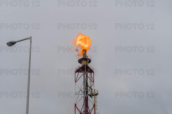 Flaring gas burns at the top of an industrial stack against a gloomy sky, in Ulsan, South Korea,
