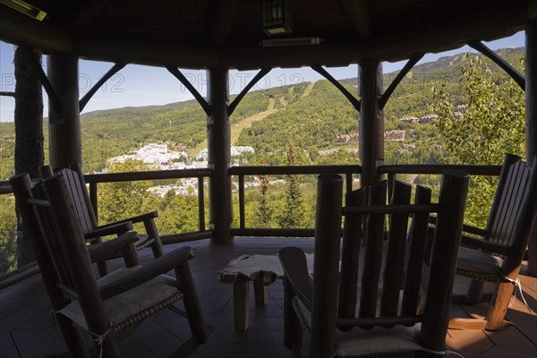 Brown stained gazebo on wooden deck with tempered glass and log railings attached to back of