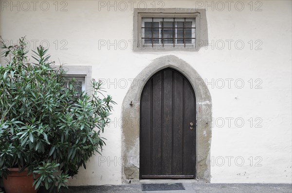 Langenburg Castle, entrance area with a wooden arched door, a small window and a potted plant,