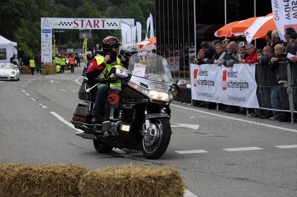 Police motorbike passing the starting line of an event, audience in the background, SOLITUDE