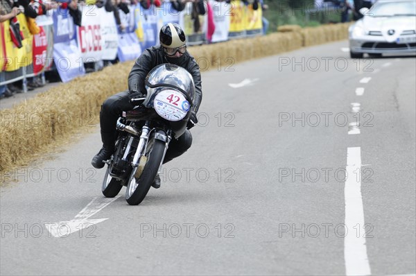 A motorbike racer concentrates on the race track, spectators in the background, SOLITUDE REVIVAL