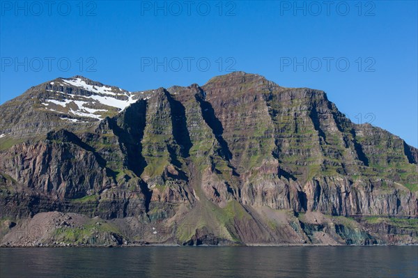 Rugged mountains and steep sea cliffs along the fjord Seyoisfjoerour, Seydisfjoerdur in summer,