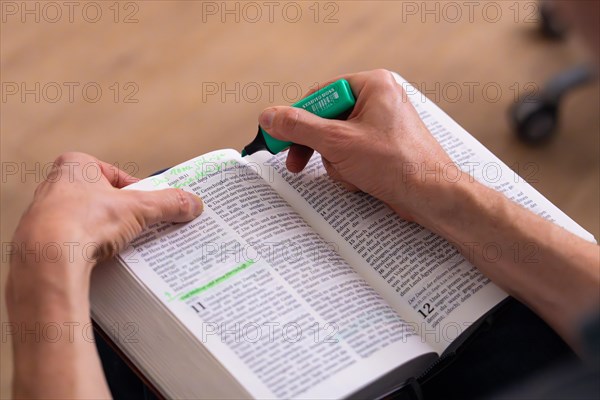 Hands holding a green highlighter and marking text in an open book, Bible Circle, Jesus Grace