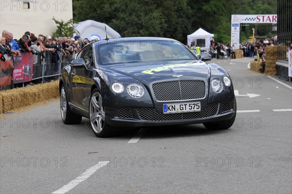 Black Bentley sports car drives along in front of spectators at a racing event, SOLITUDE REVIVAL