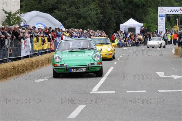 A green Porsche 911 drives on a street during an event, SOLITUDE REVIVAL 2011, Stuttgart,