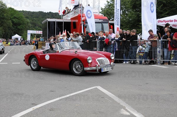A red convertible vintage car drives on a road at an event, SOLITUDE REVIVAL 2011, Stuttgart,