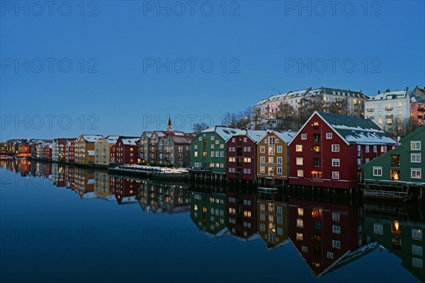 Historic warehouse buildings reflected in the river Nidelva at dusk, Bryggene, Trondheim, Norway,