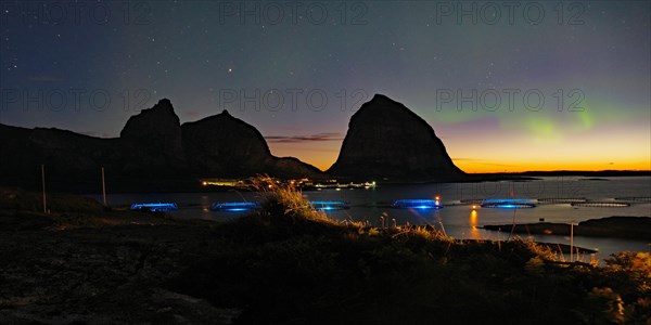 Northern lights (aurora borealis) mingle with sunset, sea, striking mountains and fish farm,