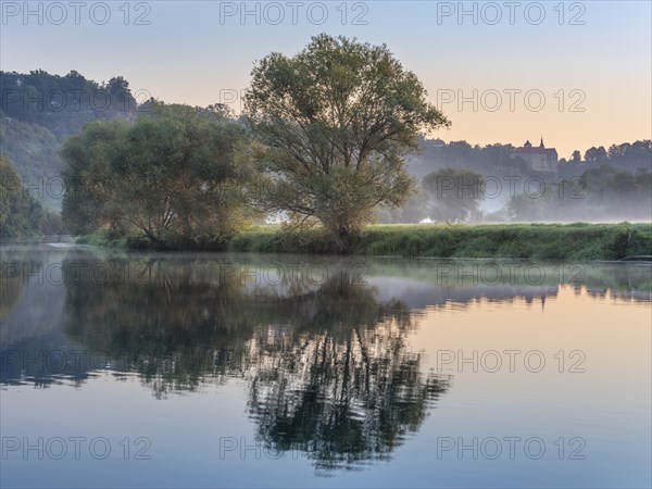 Morning atmosphere at the Saale river with morning fog, in the background Goseck Castle in the