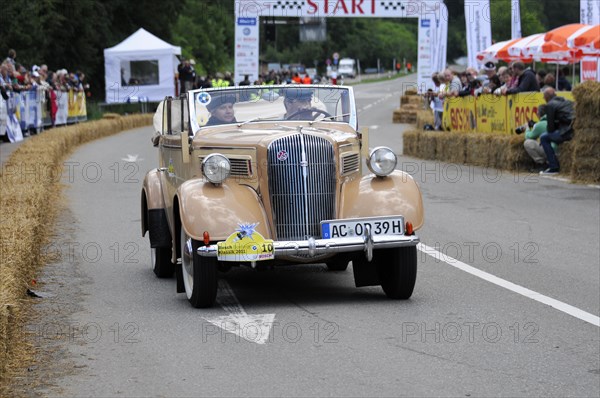 Old beige convertible driving on a road in front of an audience at a classic car race, SOLITUDE