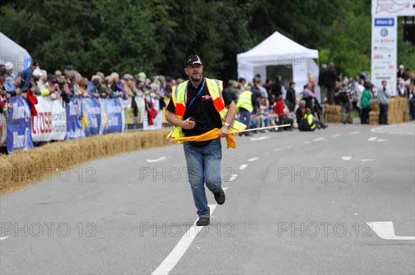 A person in a yellow safety waistcoat runs across a race track with a flag, SOLITUDE REVIVAL 2011,