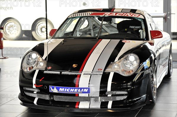 A black Porsche racing car with white and red stripes stands in the showroom, Schwaebisch Gmuend,