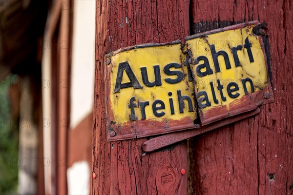 Old sign, keep exit clear, bent and rusty on wooden beam, courtyard exit, historic half-timbered
