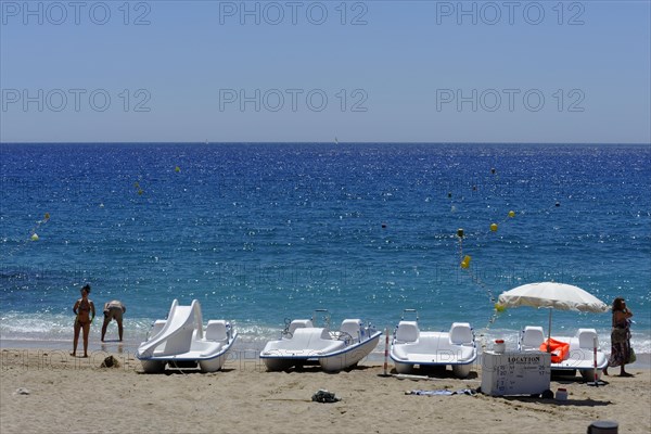 The bay of Port Miou in Cassis, A sunny beach day with people, sunbathing boats and clear blue sea,