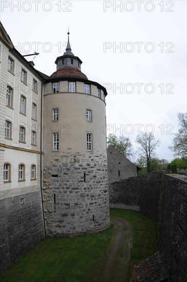 Langenburg Castle, A medieval tower on a castle wall surrounded by trees under a cloudy sky,