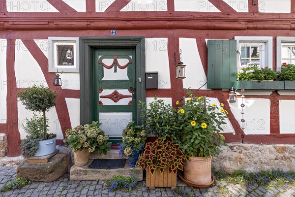 Old half-timbered house, decorated with flowers, carved entrance door, idyllic alley, old town,