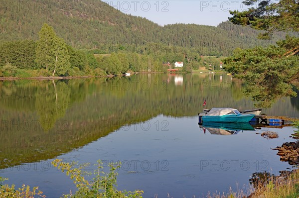 Trees and a small boat are reflected in a calm lake, old waterway, Telemark Canal, Telemark,