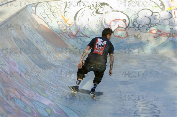 Teenager skateboarding on a ramp in a skate park decorated with graffiti, Marseille,