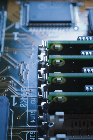 Close-up of blue and green lighted electronic computer circuit board with memory chip and lines,