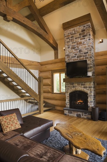 Brown leather L-shaped sofa and wooden coffee table in front of lit nuanced tan and brown natural