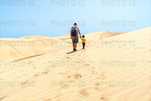 Father and son on vacation laughing running in the dunes of Maspalomas, Gran Canaria, Canary