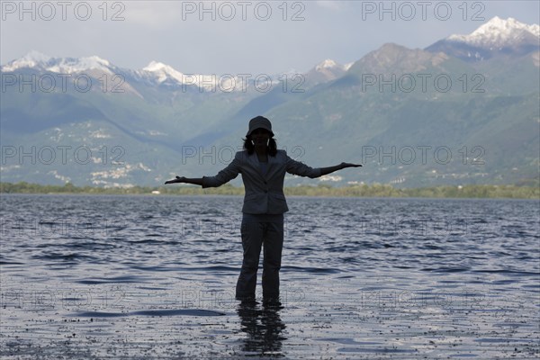 Woman Standing in a Flooding Alpine Lake Maggiore with Snowcapped Mountain in Locarno, ticino,