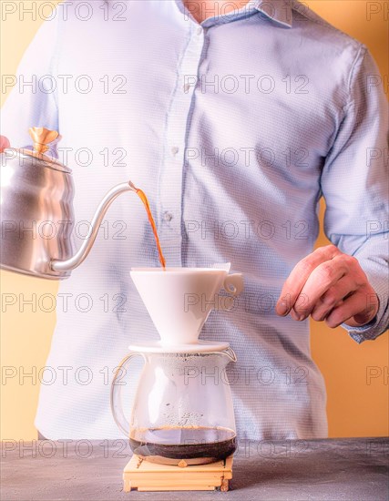 Person concentrating on manually brewing coffee with a pour-over filter setup, Vertical aspect
