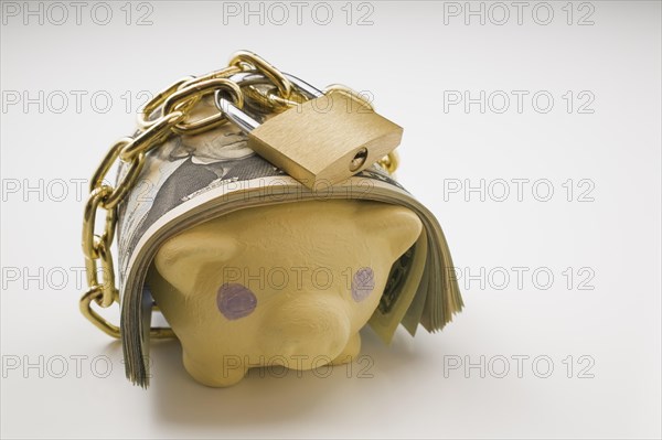 Close-up of wad of US currency bank notes wrapped with a brass chain and lock around a painted