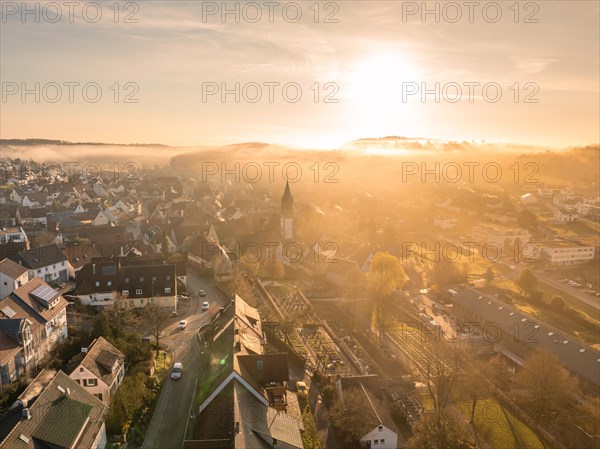 A church tower stands out as the town awakens in the sunrise light, Gechingen, Black Forest,