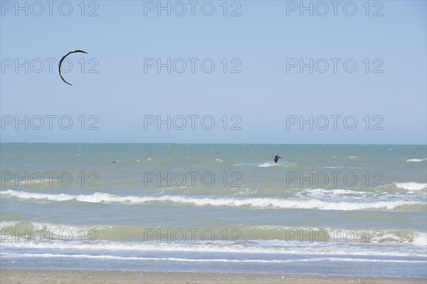 Kitesurfing Cutting Through the Waves in a Sunny Summer Day in Emilia Romagna, Rimini, Italy,
