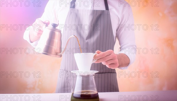 Elegant man in an apron carefully pouring hot water from a kettle into a coffee filter with steam