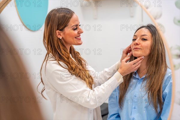 View from a mirror of a smiling aesthetic doctor analyzing the skin of an adult woman in the clinic