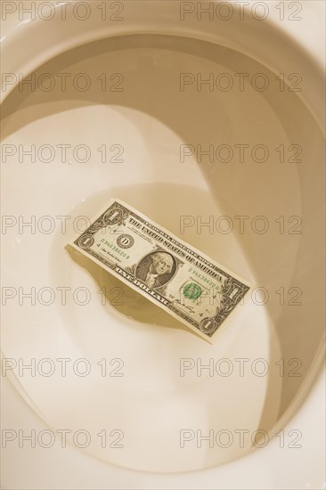 Top view and close-up of US one dollar bank note thrown down and floating in toilet bowl, Studio